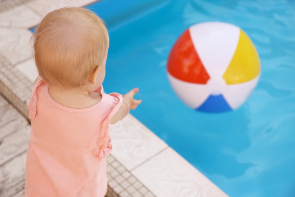 Baby throwing a ball into a pool